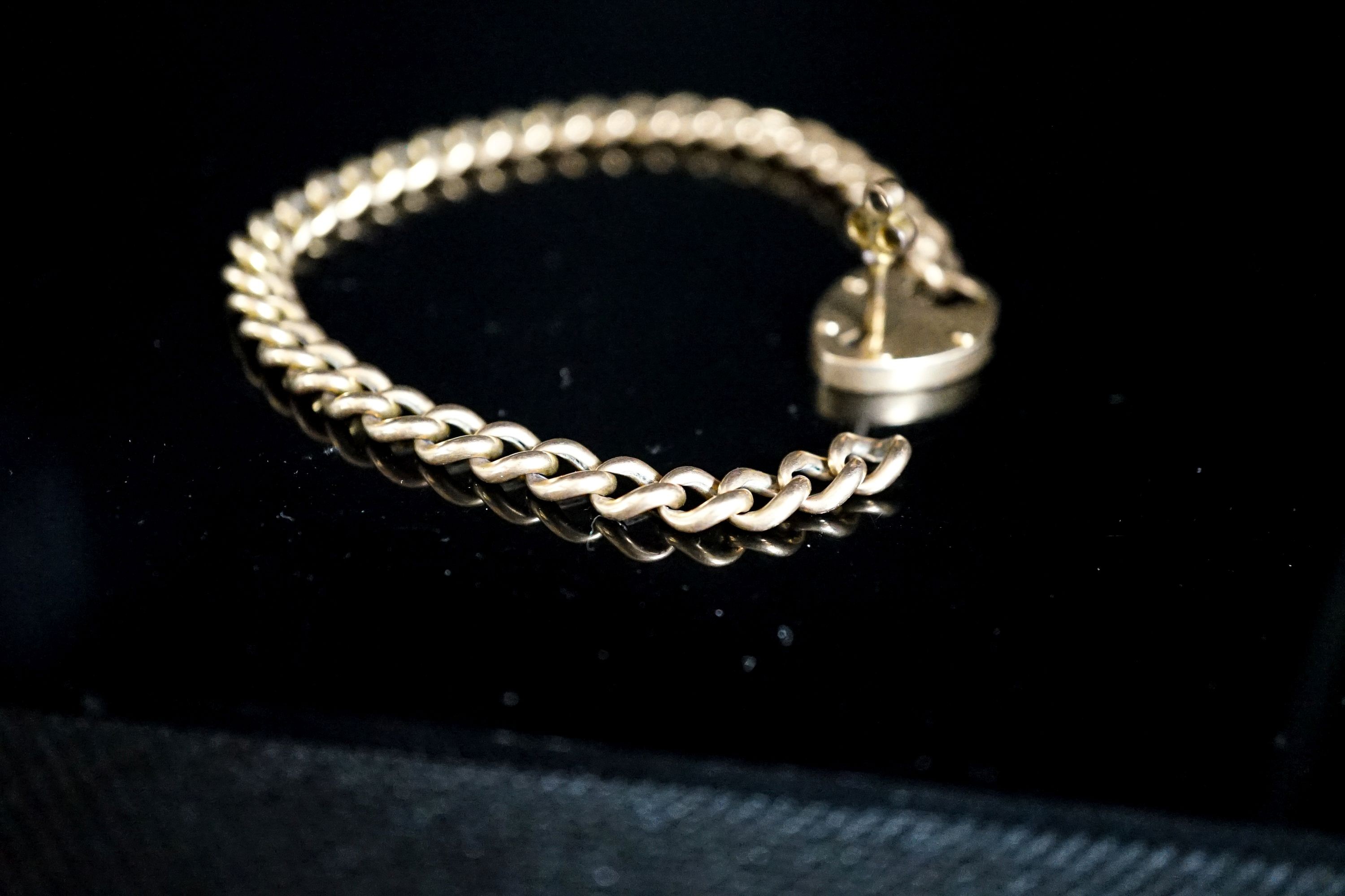 A yellow metal curb link bracelet with heart shaped clasp, with key, 20cm including clasp